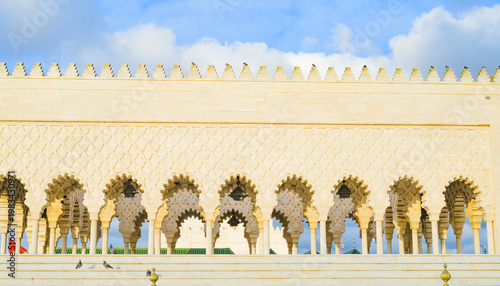 Western pavilion of the Mohammed V mausoleum in Rabat Morocco, repeating arched, gates patterns on the white marble exterior, stairs, and pigeons