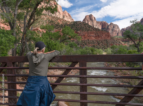Fotografía woman from behing leaning on a railing looking at the Virgin River in Zion Natio