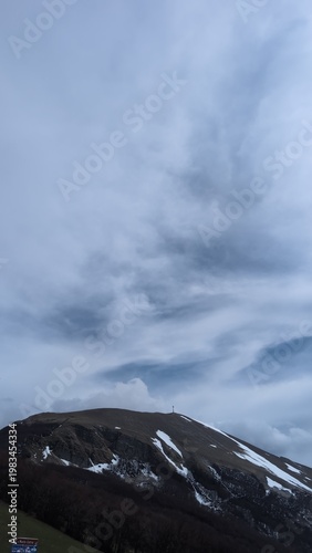 Vista da un sentiero di montagna, sotto un cielo coperto un paesaggio naturale maestoso.