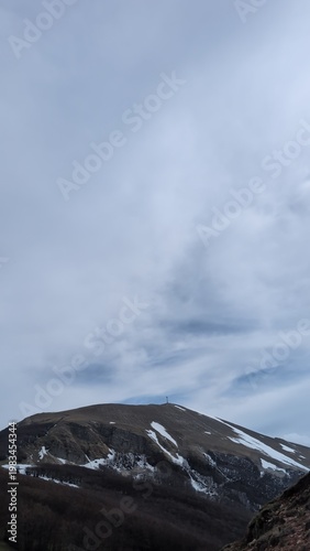 Vista da un sentiero di montagna, sotto un cielo coperto un paesaggio naturale maestoso.