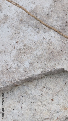 Texture superficie di una roccia di montagna chiara con crepe naturali e segni del tempo