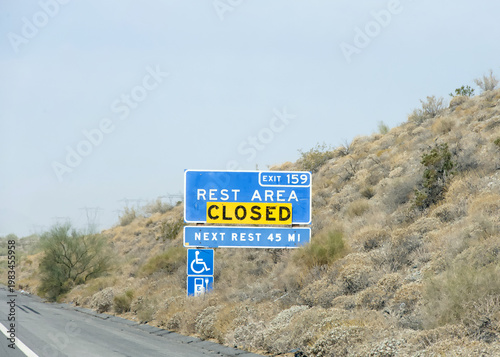 Rest area sign on the 10 freeway with closed sign over it. Desert landscape along the side of the road