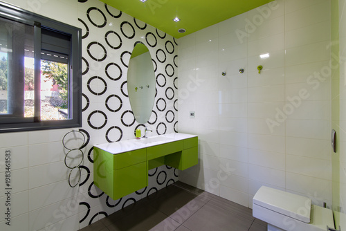 Modern bathroom interior featuring green vanity and geometric pattern wall tiles