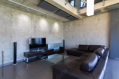 Loft living room with concrete walls, modern leather sofa, and home theater system