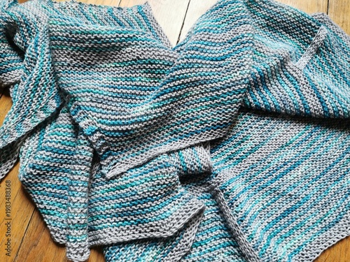 Slika na platnu Handmade knitted shawl with striped pattern laid on wooden floor