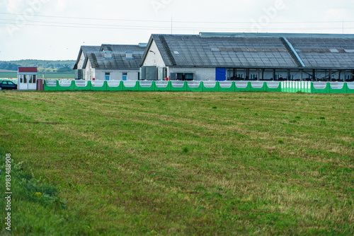 The facade of a modern cow farm building. An agro-industrial complex surrounded by a green field. Natural animal husbandry.
