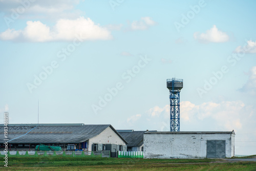 The facade of a modern cow farm building. An agro-industrial complex surrounded by a green field. Natural animal husbandry.