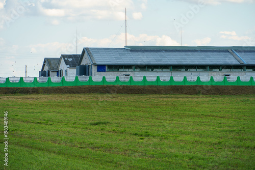 The facade of a modern cow farm building. An agro-industrial complex surrounded by a green field. Natural animal husbandry.