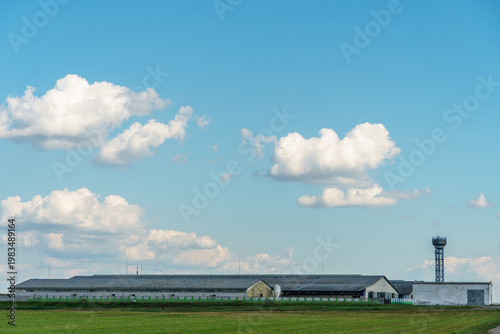 The facade of a modern cow farm building. An agro-industrial complex surrounded by a green field. Natural animal husbandry.