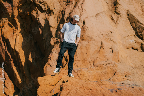 Man stands on rust-red rocky cliff