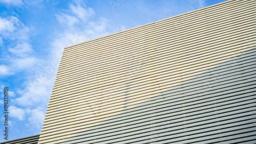 Fotografie Modern building facade with horizontal lines against a blue sky.