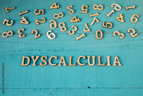 Dyscalculia word and chaotically scattered digits on a blue-painted wooden background - learning disabilities concept.