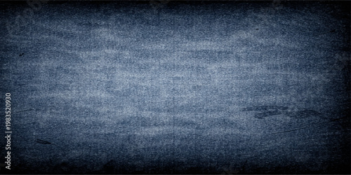 A dark blue grunge background with a textured denim fabric pattern featuring a rough vintage textile surface for a fashion backdrop design