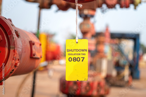 An isolation tag on oil production pipeline, during shutdown for maintenance. This is lock out tag out safety sign to inform do not operate this equipment. Industrial safety sign object, close-up and 