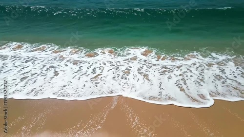 Ocean wave crashing onto a sandy beach with foamy surf