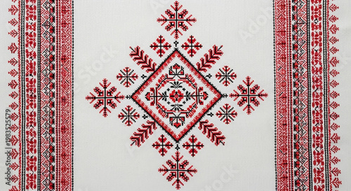 A rectangular white textile displays a symmetrical red and black embroidered diamond pattern with side borders.