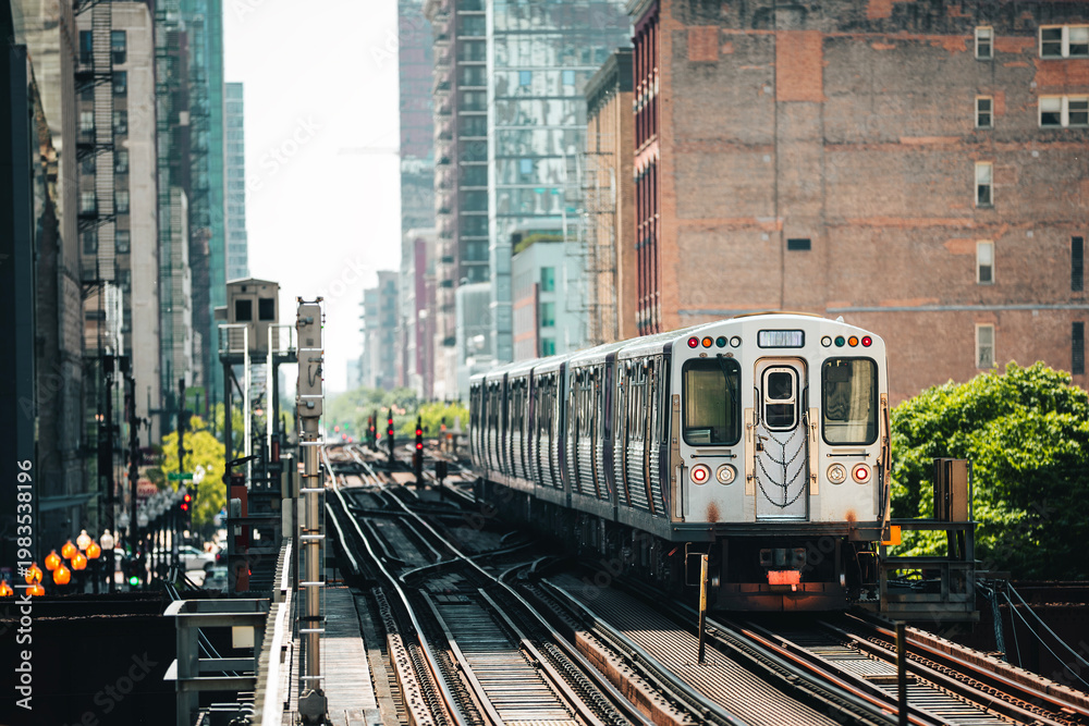 Naklejka premium Train of public transportation arriving on elevated railway above busy street in downtown Chicago. Urban transport, city life, infrastructure, and daily commute concept.