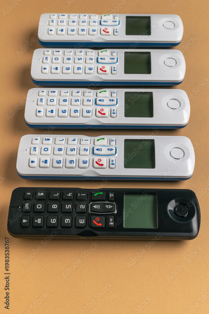 Obraz premium Collection of Cordless Landline Handsets on Brown Surface
