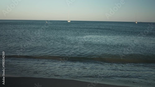 Happy young woman wrapped in a striped towel smiling and spinning on the beach at sunset