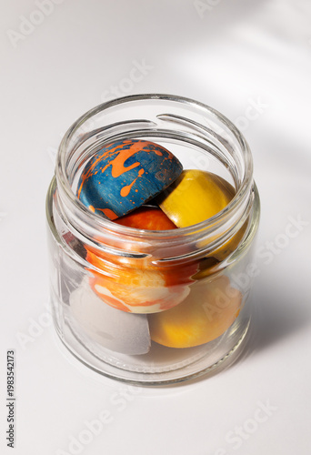 colorful round chocolate candies in a glass jar on a white background