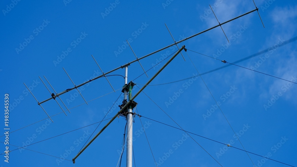 Fototapeta premium Tall VHF radio antenna with a stay ropes against a blue sky