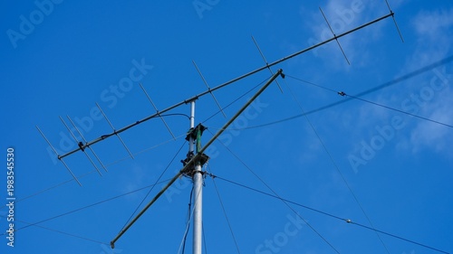 Tall VHF radio antenna with a stay ropes against a blue sky