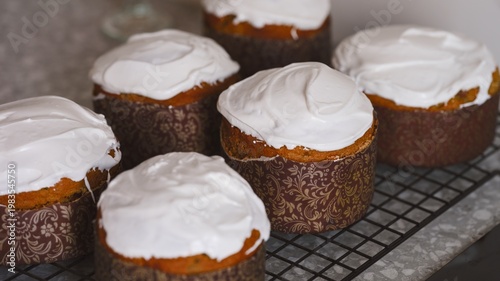 Traditional gluten free Easter cakes (Kulich Easter breads) topped with white icing cooling on a wire rack.