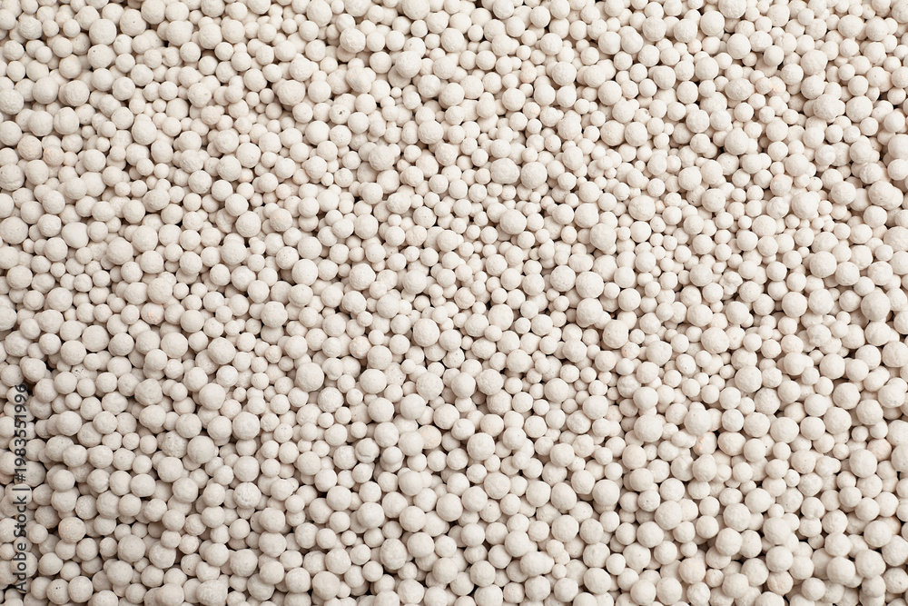 Fototapeta premium Foam glass granules in various sizes scattered on a flat surface, showcasing a light-colored substrate ideal for soil enhancement and horticultural applications