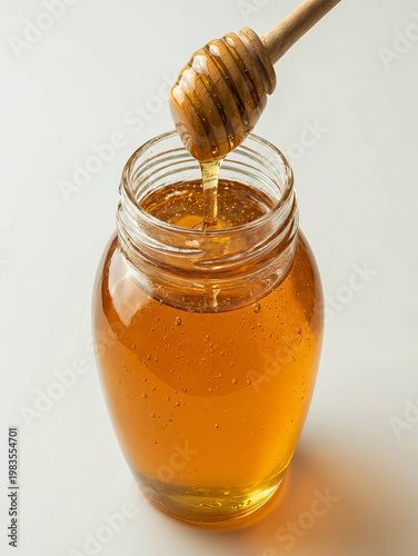 Honey being poured from a wooden dipper into a glass jar