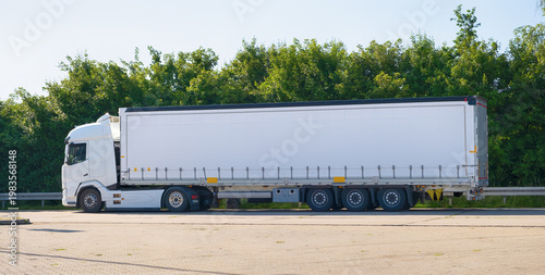 White semi truck with trailer on roadside parking, freight transport, logistics and supply chain concept. Commercial delivery vehicle for cargo shipping, trucking business, industrial transportations
