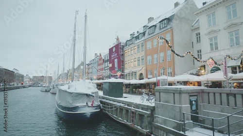 A picturesque winter view of a canal lined with vibrant buildings and boats, creating a charming atmosphere.