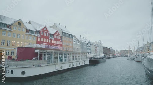 A picturesque view of vibrant waterfront buildings along a canal, with boats gently moored. The charming architecture reflects a lively atmosphere, making it an appealing sight for visitors and locals