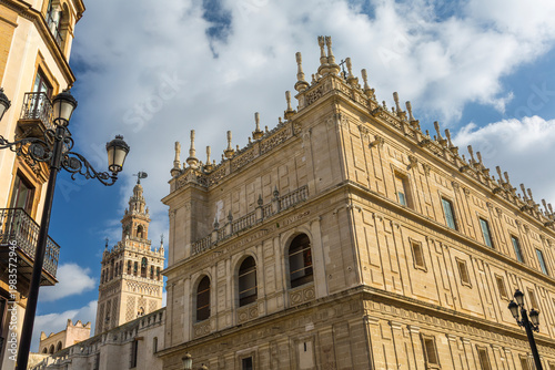Seville, Andalusia, Spain, the stunning Renaissance architecture of the Archivo General de Indias with its ornate facade and rooftop finials, alongside the iconic Giralda tower, under a blue sky