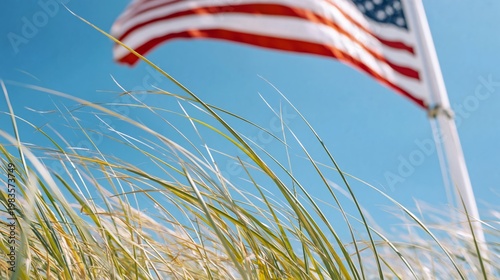 Grass Sways in the Wind Beneath an American Flag Under a Clear Blue Sky