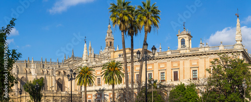 Seville, Andalusia, Spain: Panoramic view showcasing the intricate gothic architecture of Seville Cathedral alongside the elegant renaissance-style Archbishop's Palace under a clear blue sky