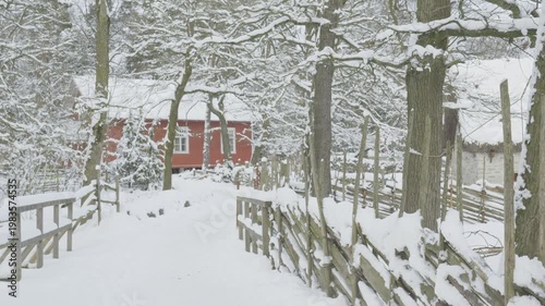 A serene winter landscape featuring a pathway lined with snow-covered trees, leading to a charming red house in the distance. The scene captures the tranquility and beauty of a snowy day.