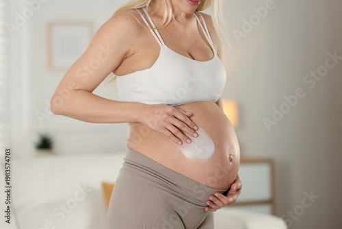 Free Download Pregnant woman applying cream onto her belly at home, closeup - GFXLoad