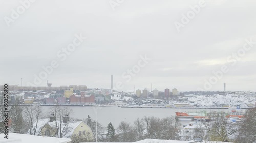 A stunning view of a snowy cityscape featuring vibrant buildings by the waterfront. The serene atmosphere captures the essence of winter, showcasing a blend of natural beauty and urban architecture.
