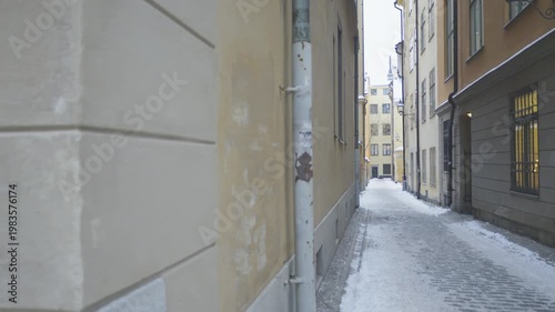 A picturesque narrow alleyway covered in snow, flanked by charming historic buildings. The peaceful atmosphere invites exploration and highlights the beauty of urban winter scenes.
