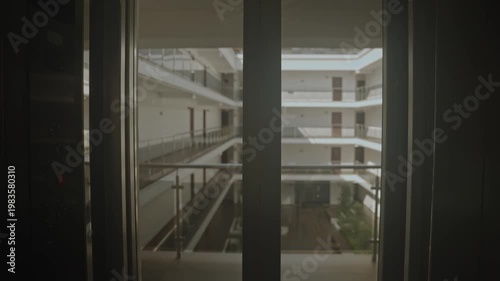 Empty Elevator Opens To Modern Atrium, Soft Morning Light Filters Through Multi Level Balconies, Reflective