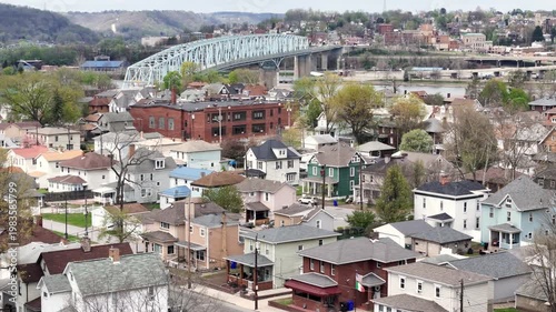 Orbiting aerial establishing shot of Monaca, Pennsylvania residential neighborhood with homes, local streets, and bridge spanning the Ohio River in the background. Pittsburgh suburbs. 15115  