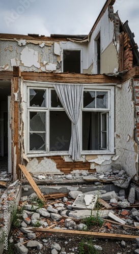 Dilapidated building facade shows broken windows and rubble from structural damage