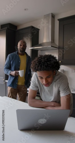 Father Supporting Child Education in Kitchen with Laptop computer Technology
