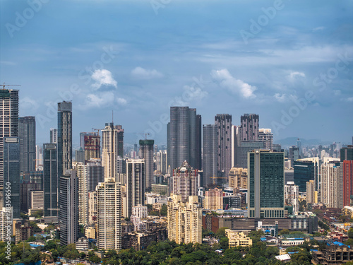 Aerial view of the modern urban skyline of Mumbai with High-Rise Buildings. A vibrant cityscape of Mumbai showcases a dense cluster of modern skyscrapers and residential towers under a clear blue sky.