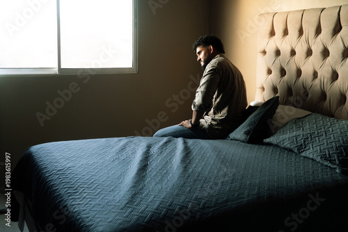 Man experiencing sadness and loneliness sitting on bed