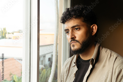 Man feeling lonely and reflecting by window