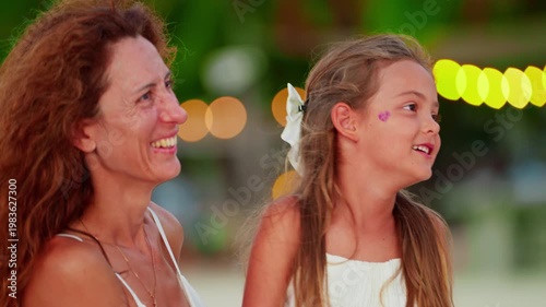 Mother and her cute little daughter spending time together laughing on the beach of a tropical island on vacation enjoying each other. Concept of motherhood childhood and spending time together