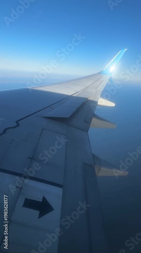 Airplane flying slightly above the clouds. Inside view through the window of an airplane of the wing and turbine. Clouds moving fast below the plane. Airplane flying high, clouds moving below. 