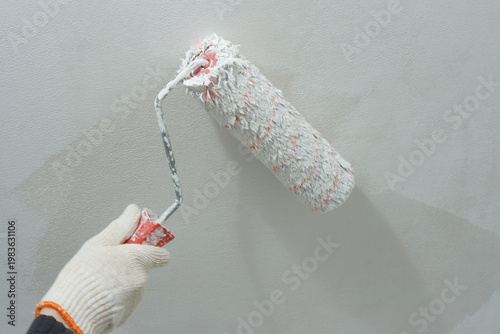 Paint roller in hand. Painting ceiling white paint.
