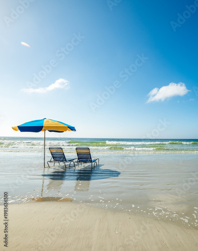 Quadro su tela Beach chairs and a parasol on the sand in a beach on a sunny day